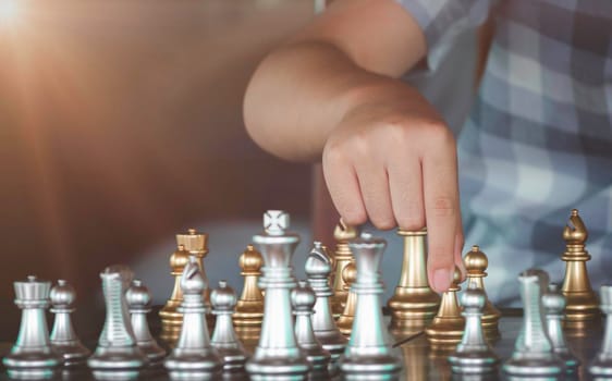 Concentrated serious boy moving gold pawn chess figure in competition success and developing chess gambit, strategy ,playing board game to winner. Learning, tactics and analysis concept.