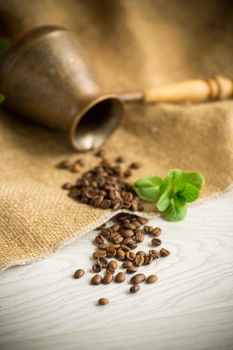 coffee beans are scattered next to a cezve on a wooden table