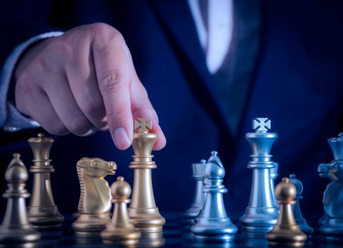 Hand of businessman holding the golden king chess to fighting silver king chess to play successfully in the competition with technology network background. Management or leadership strategy concept.