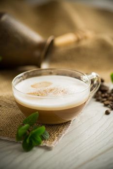 Cup of coffee latte with heart shape and coffee beans on old wooden background