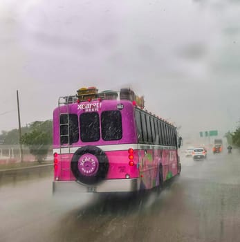 Playa del Carmen Mexico 12. March 2022 Pink Xcaret bus drives in heavy rain monsoon on the highway freeway Playa del Carmen in Quintana Roo Mexico.