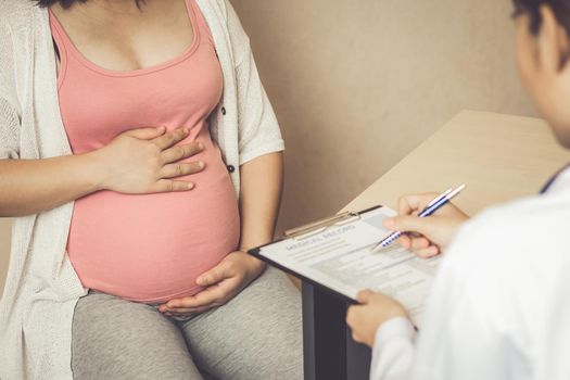 Happy pregnant woman visit gynecologist doctor at hospital or medical clinic for pregnancy consultant. Doctor examine pregnant belly for baby and mother healthcare check up. Gynecology concept.