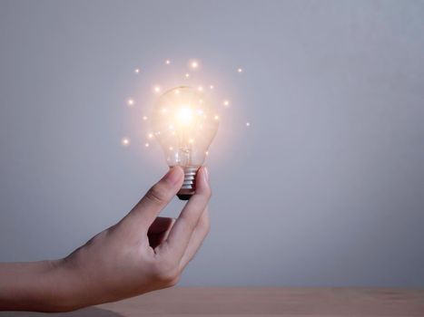 Hand of businessman holding light bulb with fire spark shine glitter for new idea with innovation and inspiration, communication and technology in science concept.