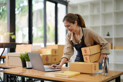 SME entrepreneur Small business entrepreneurs Online selling ideas,Happy Young Asian business owner work on computer and a boxs at home,delivery SME procurement package box deliver to customers,