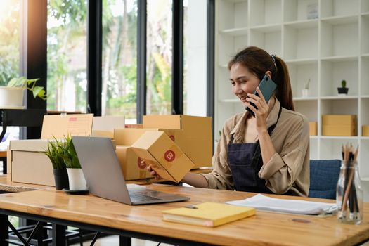 Startup SME small business entrepreneur SME or freelance Asian woman calling phone, online marketing packaging box and delivery, SME concept