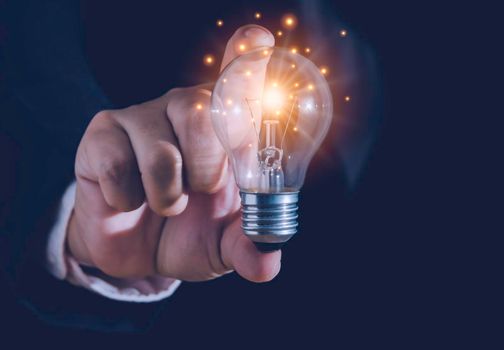 Hand of businessman holding light bulb with fire spark shine glitter for new idea with innovation and inspiration, communication and technology in science concept.