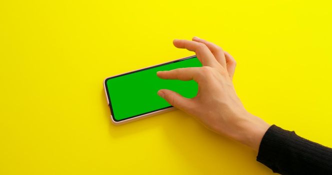 Green Mock-up Screen Chroma Key phone. Female hand touching, zoom in on smartphone screen in horizontal mode. Internet, communications concept.