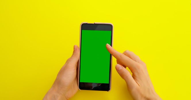 Scrolling gesture on Green Screen. Surfing internet, social media or online shop - internet, communications concept. Copy space for photoproduct placement. Phone on creative yellow background.