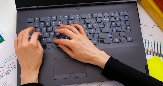 Top view woman hands typing on laptop. Keyboard typing hands. Office work. Setting goals. Writes mails, research, surfing internet. Business and finance sheets.