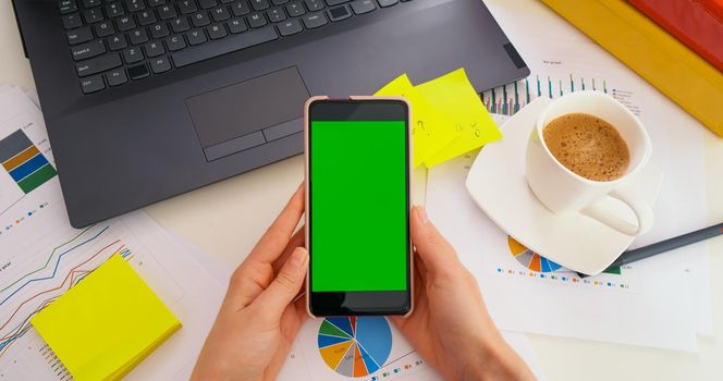 Top view of Green Screen Mock-up Chroma Key of smartphone by business woman at work. Business office, worksheet finance, graph accounts