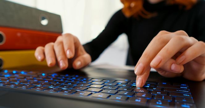 Female using laptop computer on office table background. Typing on laptop keyboard. Business and finance concept.