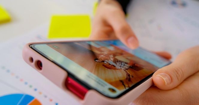 Female using smartphone on office work. Internet surf, scrolling in online search, information search. Close up macro of smartphone