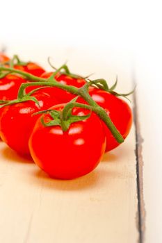 fresh cherry tomatoes on a cluster over rustic wood table