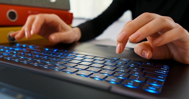 Close up female hands typing on laptop while sitting at office desk indoors. Working online, technology, office work day, business and finance concept.