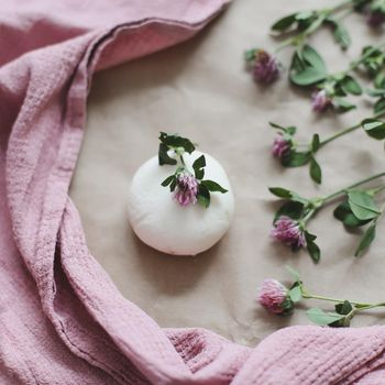 Handmade natural organic soap with flowers and pink towel on craft paper background top view with copyspace