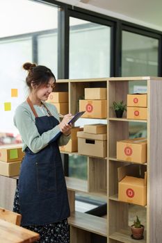 A portrait of a small startup, an SME owner, an Asian female entrepreneur checking orders to arrange the produce before packing the products in the inner boxes with the customers. Freelance concepts.