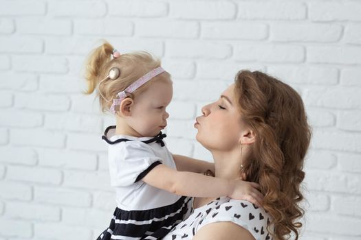 Mother helps her deaf baby daughter putting hearing aid in little girl's ear indoors - cochlear implant and innovative medical technologies