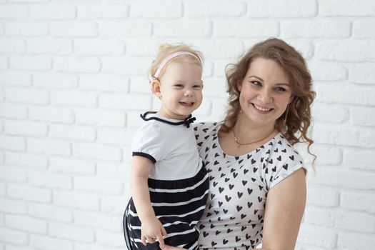 Mother helps her deaf baby daughter putting hearing aid in little girl's ear indoors - cochlear implant and innovative medical technologies