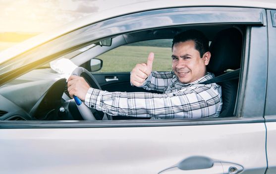 Portrait of a man showing thumbs up while driving, Man in his car giving a thumbs up, happy man in his car giving a thumbs up