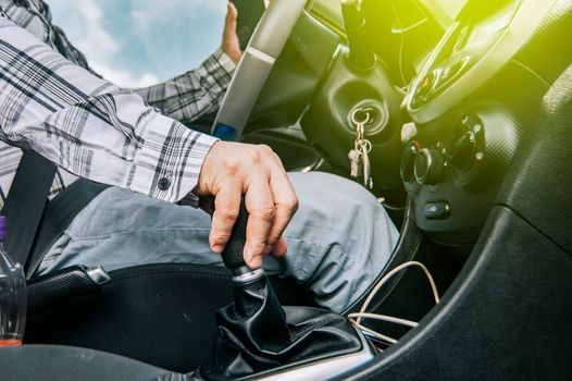 Close up of a man's hand on the gear lever of a car, concept of speed and gear lever, close up of hands accelerating on the gear lever