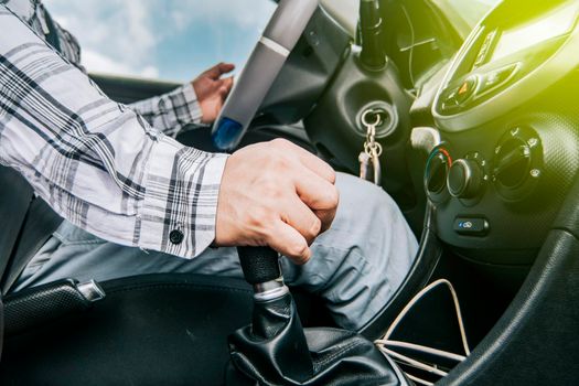 Close up of a man's hand on the gear lever of a car, concept of speed and gear lever, close up of hands accelerating on the gear lever