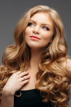 Studio fashion portrait of attractive sensual young woman with long wavy fair hair and blue eyes looking at camera. Natural beauty concept. Caucasian.