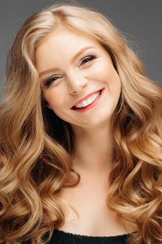 Studio fashion portrait of attractive sensual young woman with long wavy fair hair and blue eyes looking at camera. Natural beauty concept. Caucasian.