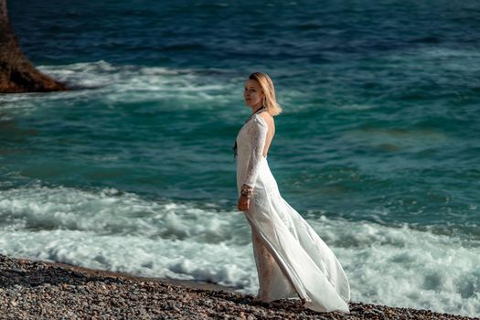 Middle aged woman looks good with blond hair, boho style in white long dress on the beach decorations on her neck and arms