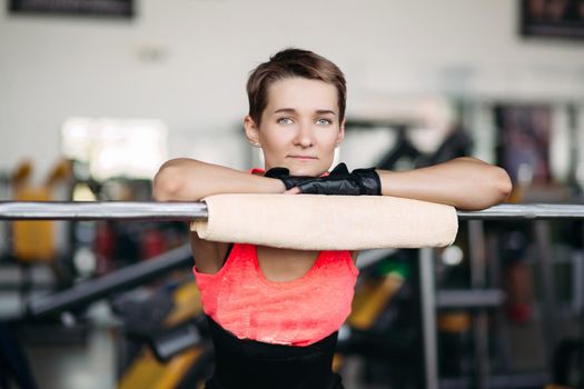 Back view of brunette woman, in pink sports wear, doing workout, with barbell. Strong woman with sporty body doing exercises alone in gym. Concept of fit and sporty lifestyle.