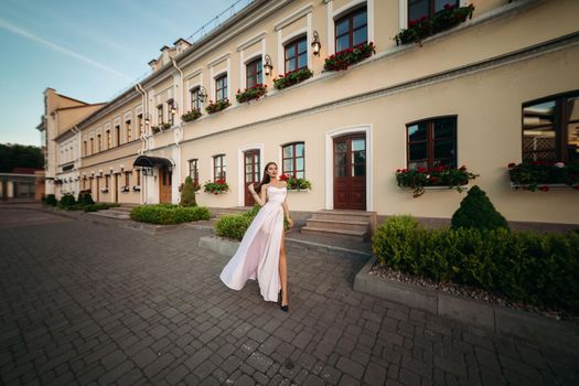 Portrait of a luxurious woman in a lush long black dress. The model is represented by a view from behind with a pensive look to the side. Against the background of a beautiful building.