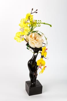 Composition with artificial flowers in a vase on white background. Ekibana from yellow artificial orchids and rose.