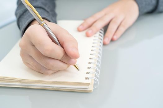 Businesswoman writing on notebook in office, hand of woman holding pen with writing notebook on desk