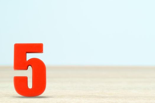 Shot of a number five made of red plastic on table with copy space