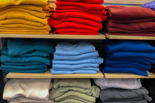 Rows of folded colorful clothes in a store