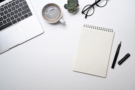 Blank notepad, glasses, coffee cup and laptop computer on white background. Top view.