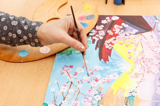 Female hand with brush painting Japanese landscape indoors
