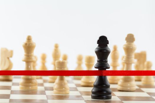 The King's figure crossing the red finish ribbon. Chess business leadership and success concept