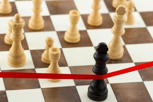 Chess business concept with King's figure crossing the red finish ribbon