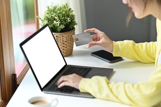 Shot of young woman holding credit card and using computer laptop for payment online or shopping online.