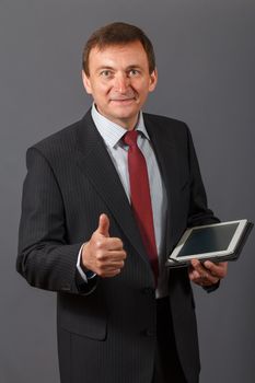 Confident and friendly elegant handsome mature businessman standing in front of a gray background holding a notebook