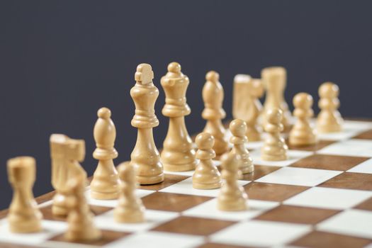 Chess board with chess pieces on gray background Selective focus on white king.