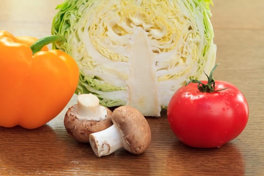 Sliced in half fresh cabbage, mushrooms, yellow pepper and red tomato on the table