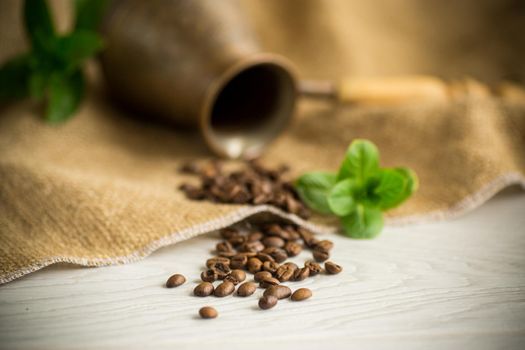 coffee beans are scattered next to a cezve on a wooden table