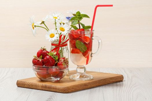 Carbonated lemonade with strawberry slices and mint on an wooden cutting board, Cold beverage for hot summer day