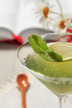 Kiwi jelly with lime piece with opened book and chamomiles on the background Close up selective focus