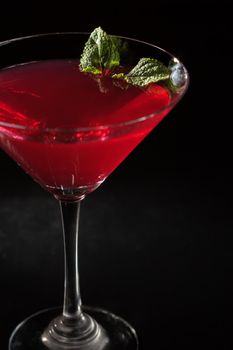 Cherry jelly with lime pieces in the glass topped mint leaves in the black background