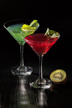 Kiwi and cherry jelly with lime pieces in the glasses topped mint leaves on the black background