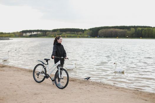 A young woman with a bicycle in the park.