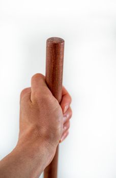 Mans hand holds brown wooden haft on white background.