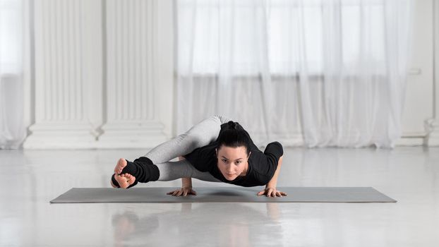 Young asian woman in yoga class making asana exercises. Girl do Eight-Angle Pose, Astavakrasana. Healthy lifestyle in fitness club. Balance hand stand.